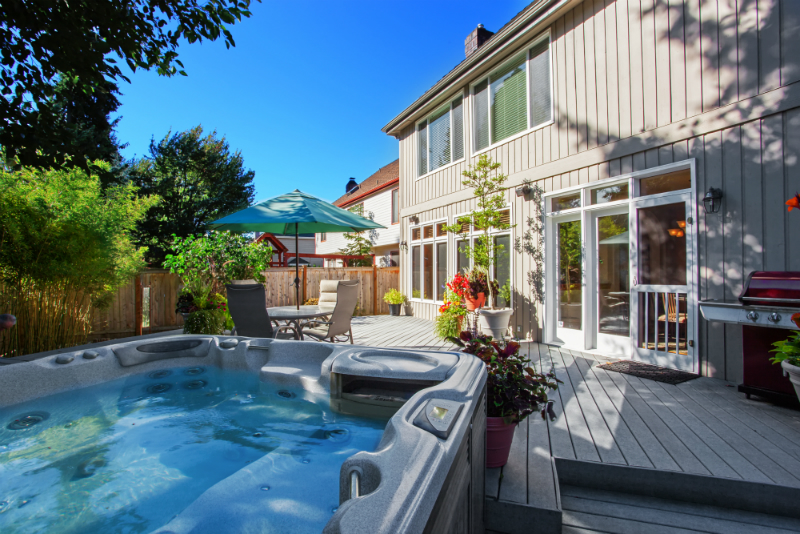 Cozy backyard with patio area and jacuzzi. Walkout deck with flower pots