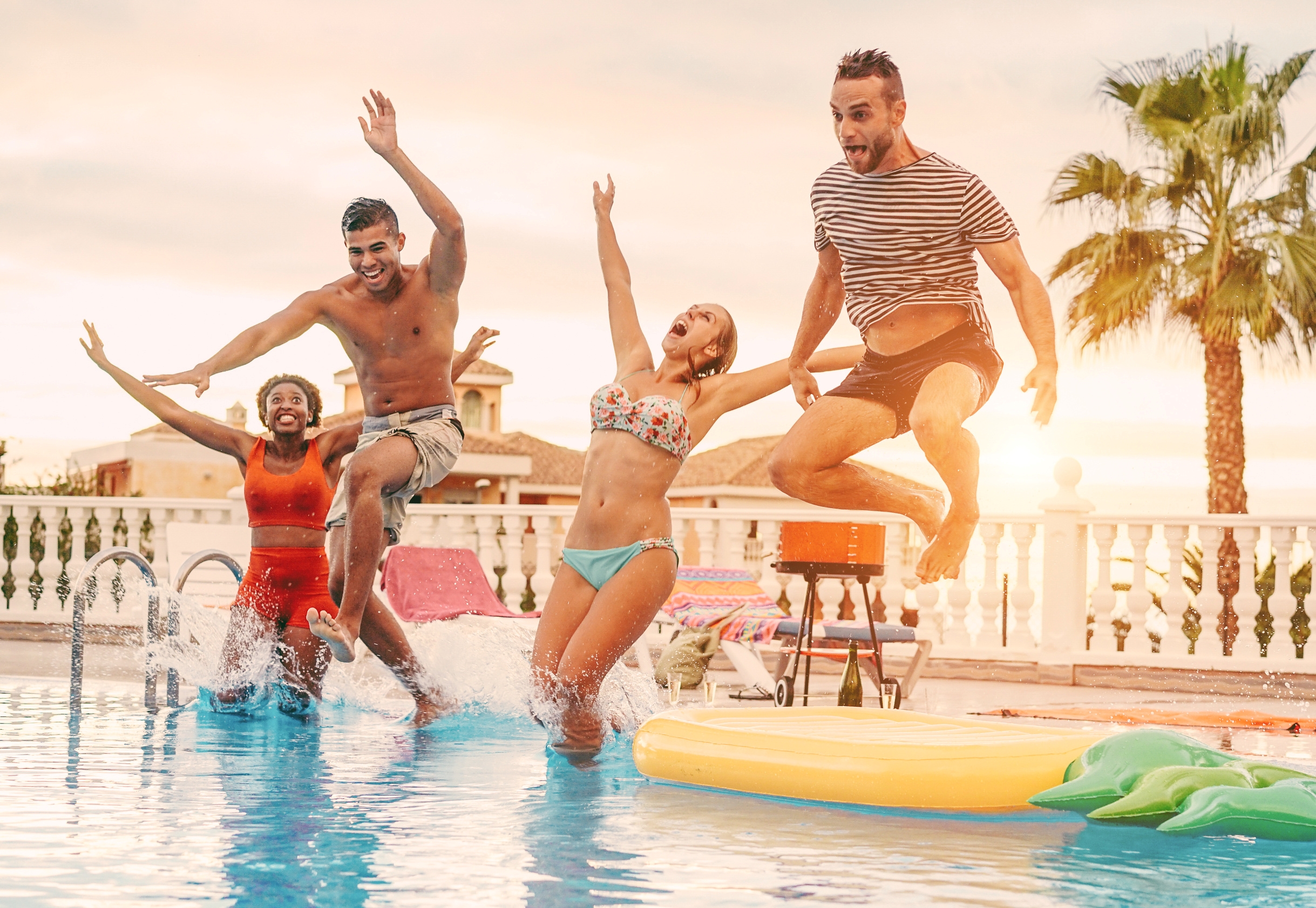 four people jumping into a pool
